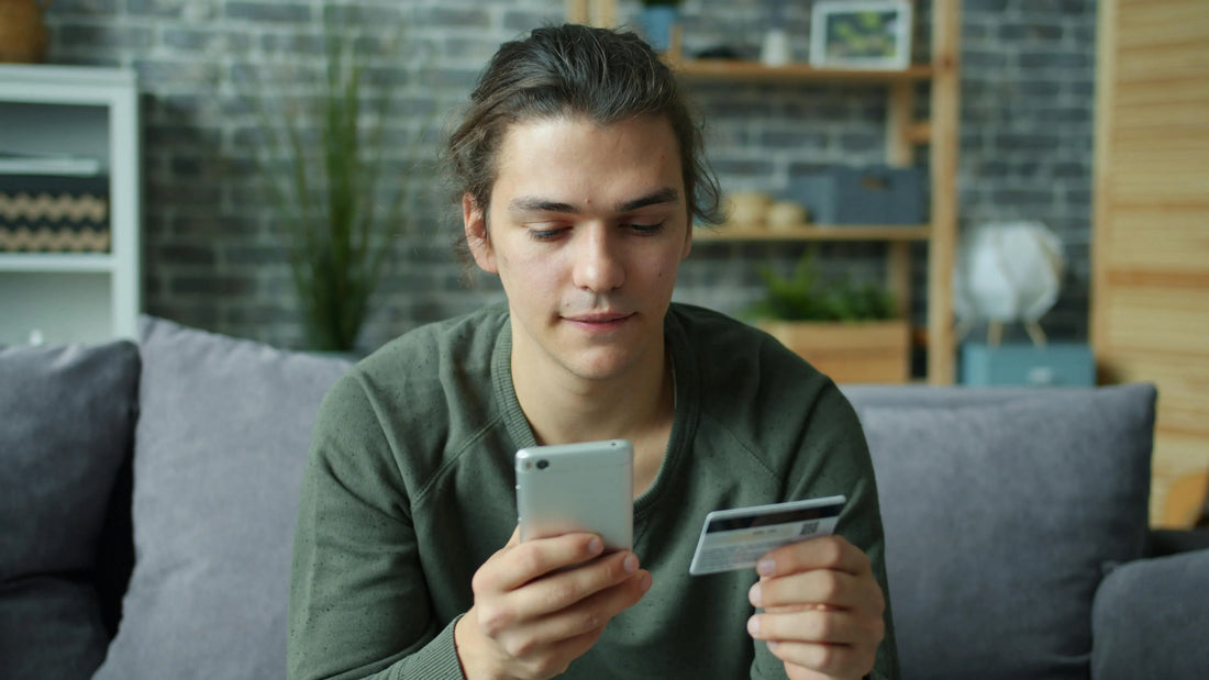 Man using a smartphone while holding a credit card