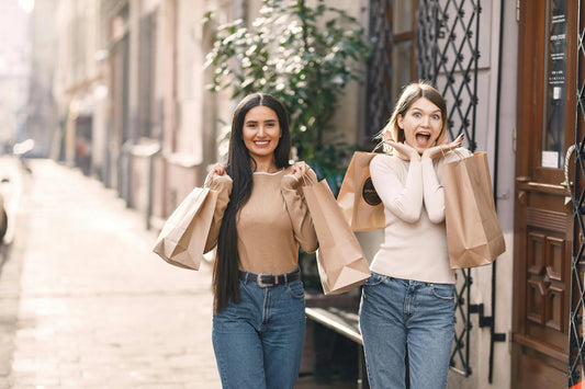 Two women enjoying shopping while holding shopping bags